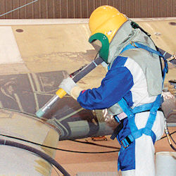 Worker in full PPE abrasive blasting