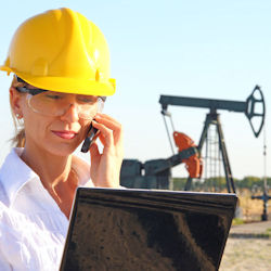 Worker on phone in front of several pump jacks