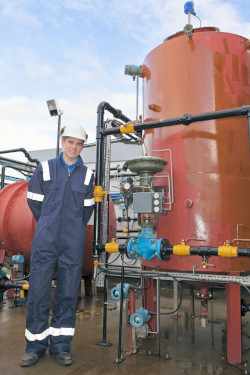 Worker standing beside large tank