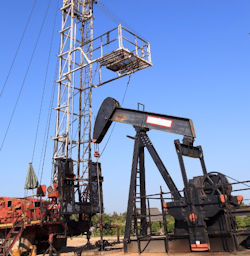 Oil pump jack (sucker rod beam) being serviced by a workover rig