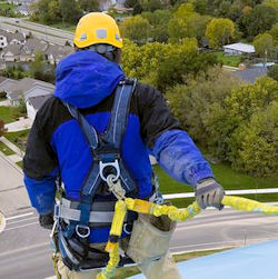Man standing on something of height. He is wearing a harness and is clipped in.