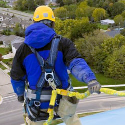 Man standing on something of height. He is wearing a harness and is safely clipped in.