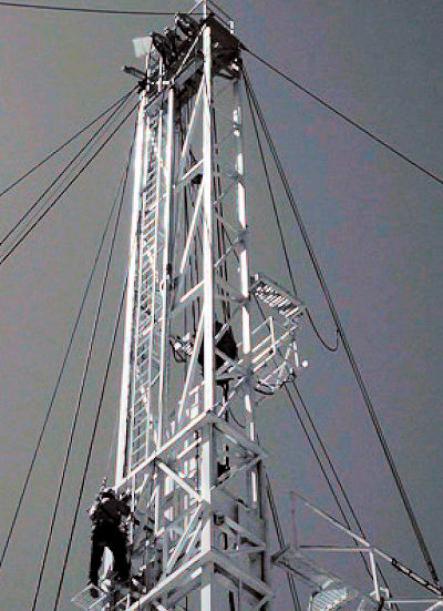 Worker climbing derrick tower ladder