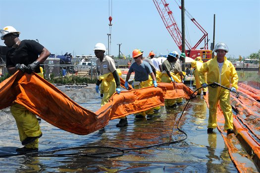 Workers using containment booms to control oil spill