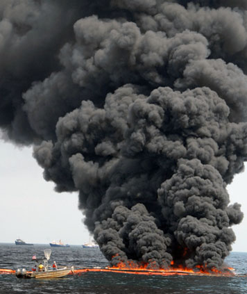 Giant plume of black some from a controlled burn of oil slick at sea